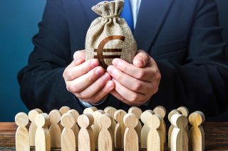 Foto: Mann mit Geldbeutel in den Hände und kleine Holzfiguren stehen davor